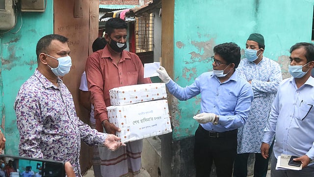 আসমাউল হুসনার স্বামীর হাতে প্রধানমন্ত্রীর উপহার তুলে দেন রাজশাহীর জেলা প্রশাসক মো. হামিদুল হক। শুক্রবার বিকেলে নগরের হেতেমখাঁ কারিগরপাড়া এলাকায়। ছবি: শহীদুল ইসলাম