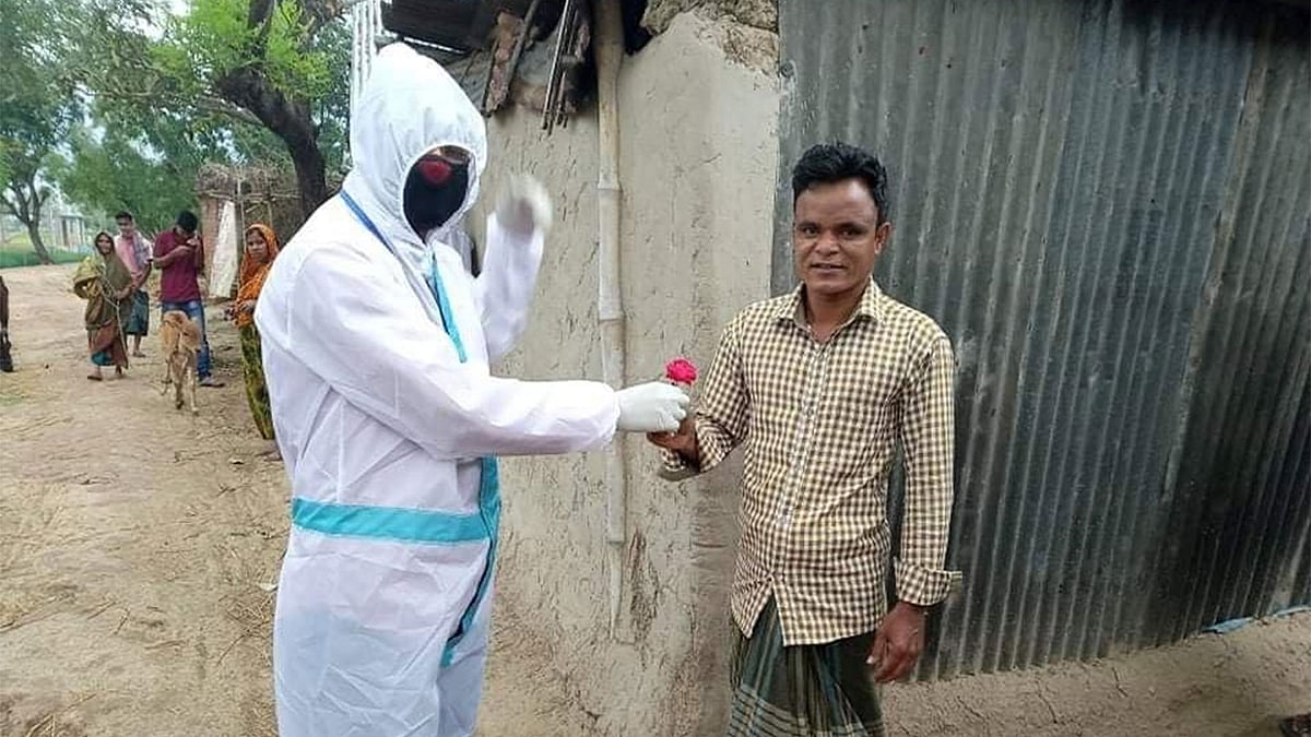 জয়পুরহাটের আক্কেলপুরে করোনা নেগেটিভ আসা এক ব্যক্তিকে গোলাপের শুভেচ্ছা জানাচ্ছেন একজন স্বেচ্ছাসেবী। ছবি: প্রথম আলো