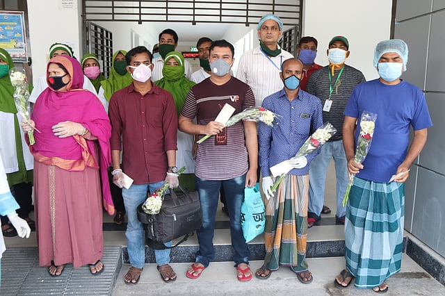 বগুড়ার মোহাম্মদ আলী হাসপাতালের আইসোলেশন ইউনিটে চিকিৎসা নিয়ে সুস্থ হওয়ার পর বাড়ি ফেরার সময় পাঁচ ব্যক্তিকে ফুল দিয়ে শুভেচ্ছা জানান চিকিৎসক ও স্বাস্থ্যকর্মীরা। গতকাল বুধবার তোলা ছবি: প্রথম আলো