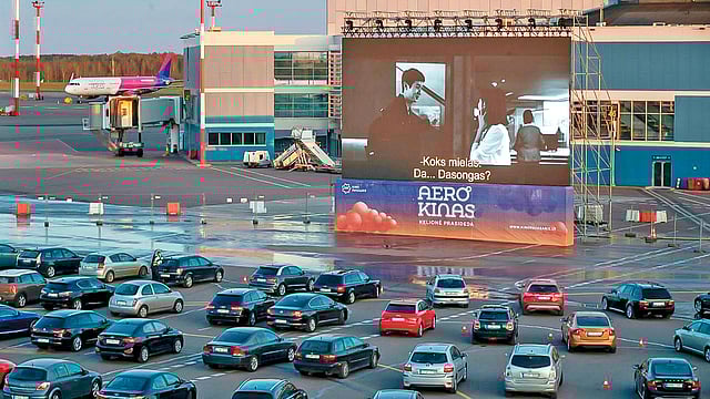 বিমানবন্দরের রানওয়েতে গাড়িতে বসে দর্শক, পর্দায় চলছে সিনেমা