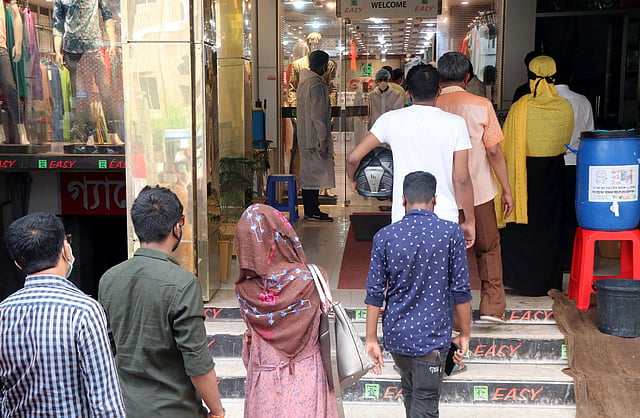 করোনা সংক্রমণের ঝুঁকি নিয়ে লাইন ধরে বিপনিবিতাণে কেনাকাটার জন্য ঢুকছেন ক্রেতারা। ফটকেই মাপা হচ্ছে শরীরের তাপমাত্রা। জলেশ্বরীতলা, বগুড়া শহর, ১৮ মে। ছবি: সোয়েল রানা