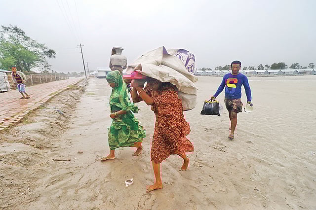 আম্পানের প্রভাবে প্রবল ঝড় শুরু হলে খুলনার কয়রা উপজেলার মঠবাড়ি এলাকায় গুচ্ছগ্রামের বাসিন্দারা ঘরের মালামাল নিয়ে ছোটেন মঠবাড়ি শান্তিময়ী সরকারি প্রাথমিক বিদ্যালয় আশ্রয়কেন্দ্রের দিকে। গতকাল বিকেল চারটায়। ছবি: সাদ্দাম হোসেন
