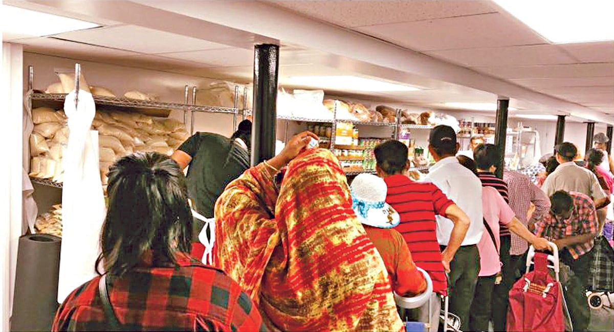 স্যাকএস থেকে লাইনে দাঁড়িয়ে মানুষ গ্রোসারি সংগ্রহ করছে