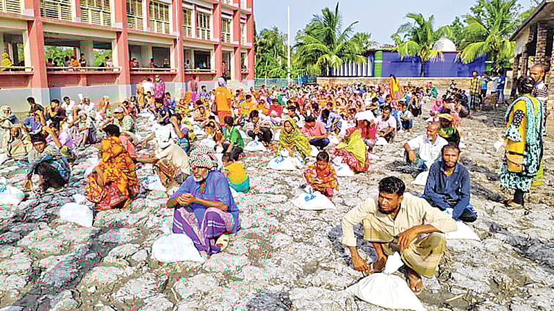 সাতক্ষীরার শ্যামনগর উপজেলার বড় গাবুরা গ্রামের গাবুরা খোলপেটুয়া সরকারি প্রাথমিক বিদ্যালয় চত্বরে প্রথম আলো ট্রাস্টের পক্ষ থেকে পাঁচটি গ্রামের ৪০০ পরিবারকে খাদ্যসহায়তা দেওয়া হয়। গতকাল বিকেলে।  ছবি: প্রথম আলো