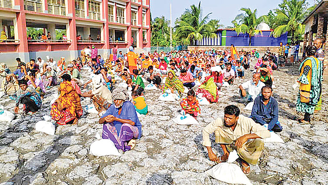 সাতক্ষীরার শ্যামনগর উপজেলার বড় গাবুরা গ্রামের গাবুরা খোলপেটুয়া সরকারি প্রাথমিক বিদ্যালয় চত্বরে প্রথম আলো ট্রাস্টের পক্ষ থেকে পাঁচটি গ্রামের ৪০০ পরিবারকে খাদ্যসহায়তা দেওয়া হয়। গতকাল বিকেলে।  ছবি: প্রথম আলো