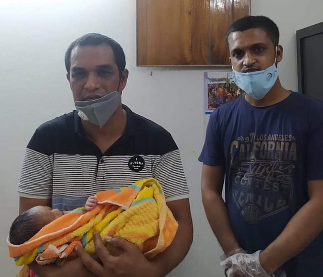 উদ্ধারের পর পাহাড়পুর পুলিশ ফাঁড়ির পরিদর্শক মনিরুল ইসলামের কোলে নবজাতকটি। ছবি: সংগৃহীত