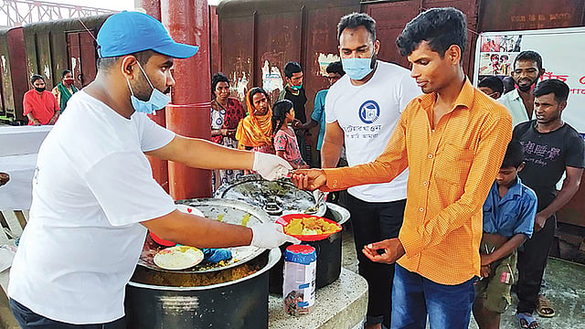 পাঁচ টাকায় দরিদ্রদের মধ্যে খিচুড়ি বিক্রি করছে জামালপুরের স্বেচ্ছাসেবী সংগঠন ‘আমরা ফাউন্ডেশন’ । শুক্রবার দুপুরে জামালপুর রেলওয়ে স্টেশনে।  ছবি: প্রথম আলো