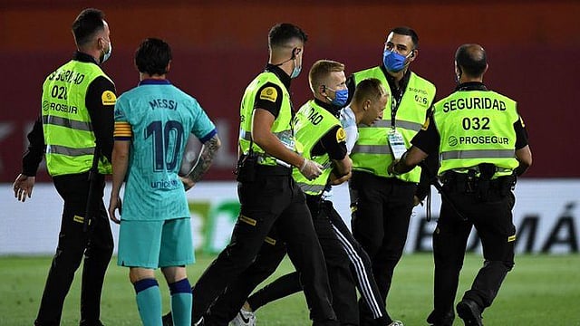 ফরাসি এ ভক্তকে বগলদাবা করে মাঠের বাইরে নিয়ে যাচ্ছেন নিরাপত্তারক্ষীরা। মেসি তা দেখছেন। ছবি: টুইটার