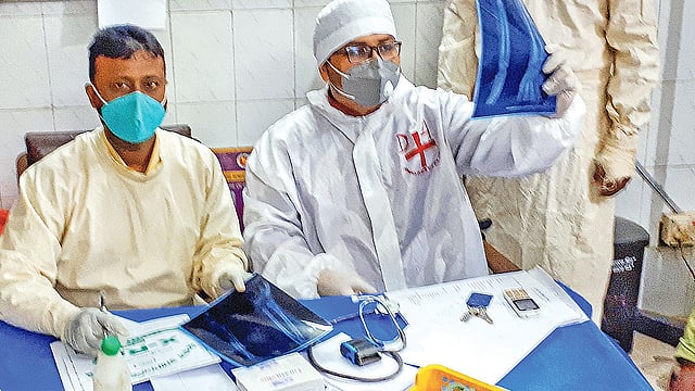 হাসপাতালে কর্মরত সাদা পিপিই পরে লেখক, পাশে তাঁর মেডিকেল সহকারী। পরপর দুজনই করোনায় আক্রান্ত হয়েছেন।  ছবি: লেখকের পাঠানো