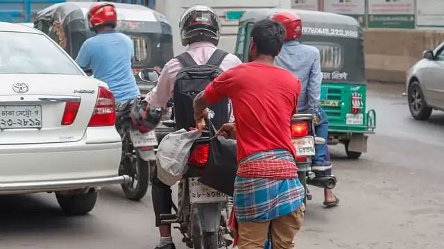 সার্ক ফোয়ারার মোড়ে মোটরসাইকেলের পেছনের ব্যাগ কাটার চেষ্টা করছে সোহেল। ছবি: সাজিদ হোসেন