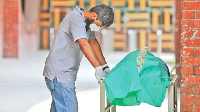 সোহরাওয়ার্দী হাসপাতালের ওয়ার্ড মাস্টার ইয়াকুব আলী চৌধুরী। দায়িত্বরত অবস্থায় করোনার উপসর্গ দেখা দিলে সেখানেই চিকিৎসা নিচ্ছিলেন তিনি। শ্বাসকষ্ট বাড়তে থাকলে বৃহস্পতিবার তাঁর নমুনা পরীক্ষা করা হয়। কিন্তু যখন জানা গেল তিনি করোনা পজিটিভ, তখন আর বেঁচে নেই। গতকাল দুপুরে তাঁর মৃতদেহের পাশে নির্বাক দাঁড়িয়ে ছোট ছেলে হাসান।  ছবি: সাইফুল ইসলাম