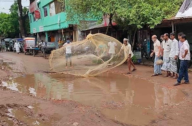 নাটোর–বাগাতিপাড়া সড়কের তমালতলা অংশ সংস্কারের দাবিতে এলাকাবাসী আজ সোমবার সকালে জাল ফেলে প্রতিবাদ জানান। ছবি: প্রথম আলো