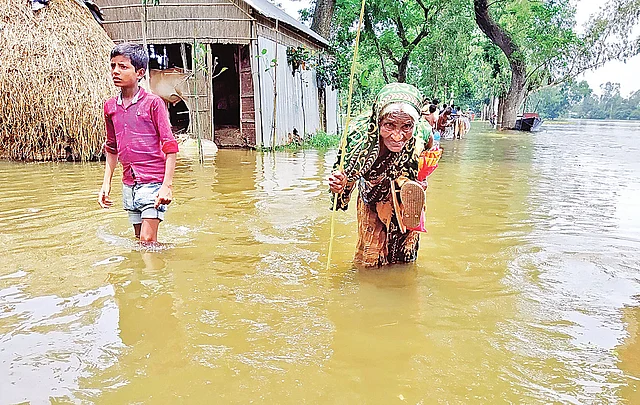 বন্যার পানির মধ্যেই খাবারের খোঁজে বেরিয়েছেন বয়সের ভারে নুয়ে পড়া, অসুস্থ আয়শা বেগম। গতকাল দুপুরে জামালপুরের দেওয়ানগঞ্জ উপজেলার বালুগ্রামে।  ছবি: আব্দুল আজিজ