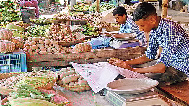 বাজারে ক্রেতা নেই বললেই চলে। তাই কাঁচাবাজারের পসরা বসিয়ে পত্রিকায় খবর পড়ছেন এক বিক্রেতা। বৃহস্পতিবার সিলেটের দক্ষিণ সুরমার চৌধুরীবাজারে।  ছবি: আনিস মাহমুদ