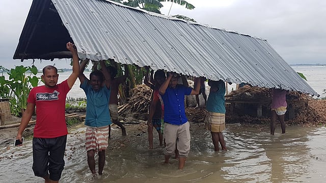 তিস্তা নদীর বন্যায় নীলফামারীর ডিমলার বিভিন্ন গ্রামে বিলীন হচ্ছে বসতঘর ও আবাদি জমি। অনেকে ভাঙনের মুখে তাদের বসতঘর সরিয়ে নিচ্ছেন। রোববার দুপুরে উপজেলার টেপাখড়িবাড়ি ইউনিয়নের টাপুর চর গ্রামে। ছবি: প্রথম আলো