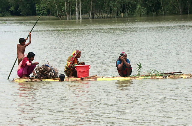 সহায়সম্বল নিয়ে কলাগাছের ভেলায় করে বাঁধে যাচ্ছে বানভাসি মানুষেরা। সারিয়াকান্দির রৌহদহ এলাকায়। প্রথম আলো