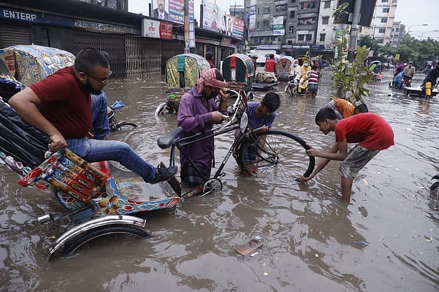 জলাবদ্ধতার মধ্যে সড়কে থাকা গর্তে পড়ে গেছে রিকশার চাকা। দয়াগঞ্জ, ঢাকা, ২১ জুলাই। ছবি: দীপু মালাকার