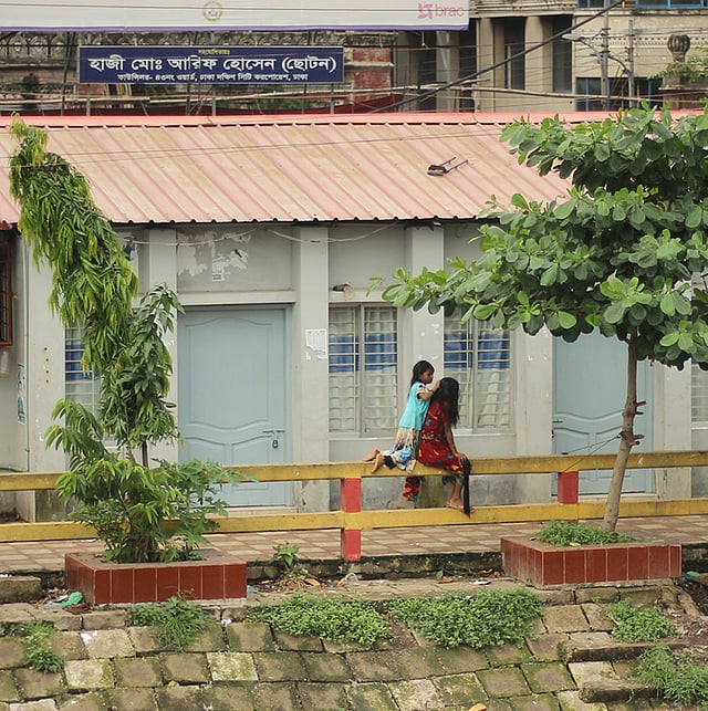 ভালোবাসা সব জায়গাতেই আছে। মায়ের চুলে বেণি করে দিচ্ছে এক পথশিশু। সদরঘাট, ঢাকা, ২১ জুলাই। ছবি: আফজাল তাহফি রোহান