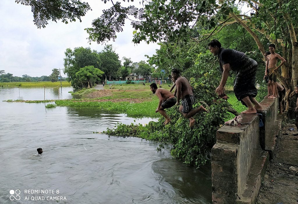 বর্ষাকাল এলেই পানিতে পূর্ণ হয়ে যায় খাল-বিল, নদী-নালা। আর শিশু-কিশোরেরাও আনন্দে মেতে ওঠে বর্ষার নতুন পানিতে। বেলা হলেই এসব জলাধারের স্বচ্ছ পানিতে ঝাঁপিয়ে পড়ে গ্রামের দুরন্ত শিশু-কিশোরেরা। বড়রাও যেন ফিরে যেতে চান সেই ফেলে আসা শৈশবের দুরন্তপনায়। উঁচু স্থান থেকে শিশুদের মতো লাফঝাঁপে কিছুক্ষণের জন্য তাঁরাও ফিরে গিয়েছিলেন মধুর শৈশবে। কাশিয়ানী, গোপালগঞ্জ, ২৯ জুলাই। ছবি: ওবাইদুল্লাহ অনিক