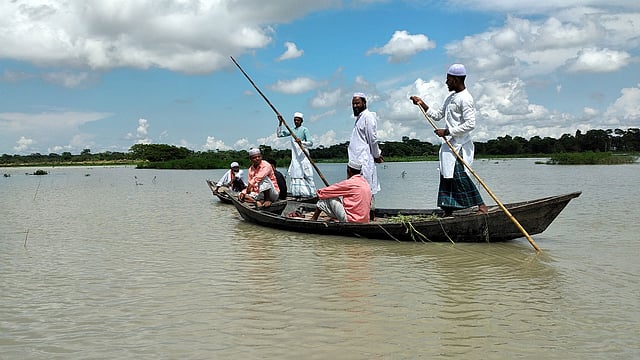 বন্যার পানিতে গ্রাম প্লাবিত। নৌকা ছাড়া চলাচল করা যায় না। ঈদের নামাজ পড়তে নৌকা নিয়ে বের হয়েছেন একদল মানুষ। আজ শনিবার সকালে নড়িয়ার মোক্তারের চর এলাকায়। ছবি: প্রথম আলো