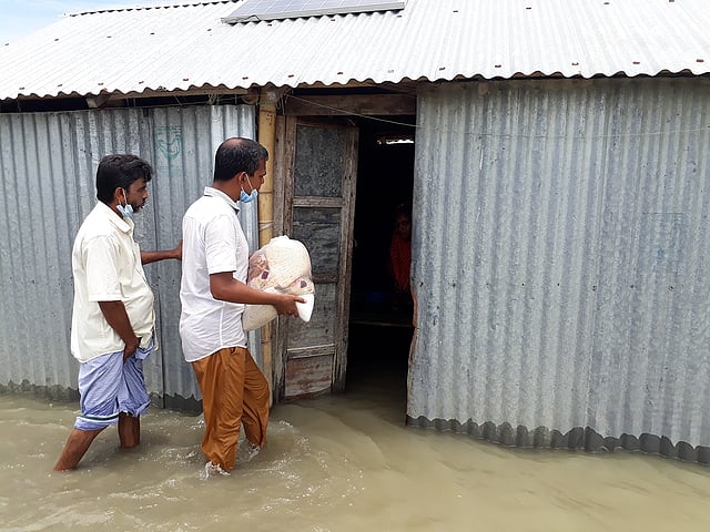 বন্যার পানিতে ডুবে গেছে বাড়িঘর। তাদের কাছে ঈদের কোনো আমেজ নেই। হয়নি ঈদ বাজারও। বন্যার্তদের ঈদসামগ্রী প্রদান করছেন আওয়ামী লীগের স্থানীয় নেতা ফজলুল হক কাওছার মোল্যা। কাঁচিকাট, সখিপুর, শরীয়তপুর, ৩১ জুলাই। ছবি: আসিফ আহমেদ