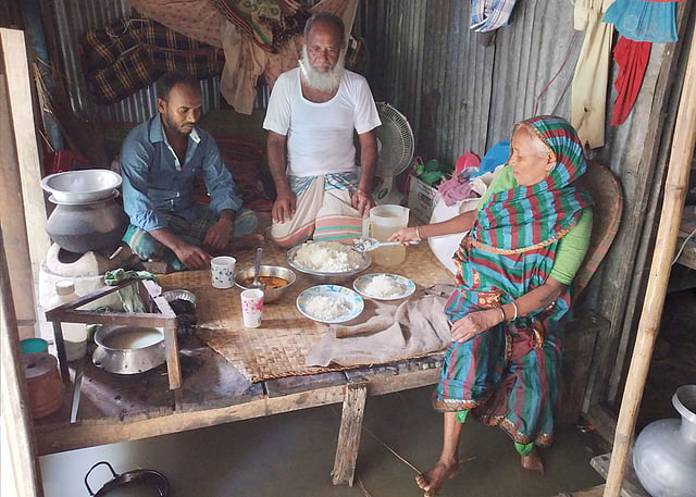 মোতালেব খানের বাড়িতে এ বছর ঈদের কোনো আয়োজন নেই। বাড়িতে যা রান্না হয়েছে, পরিবারের সদস্যদের নিয়ে তা–ই খেতে বসেছেন। আজ শনিবার সকালে নড়িয়ার মোক্তারের চর এলাকায়। ছবি: প্রথম আলো