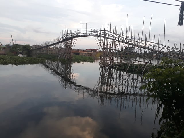 রাজধানীর বালুর পাড়ে বালু নদের ওপর কংক্রিটের সেতু নেই, কিন্তু আছে বাঁশের বড় এক সেতু। সে সেতু দিয়ে বন্যার এই সময়ে চলাচল করছে মানুষ। ছবি: আসাদুজ্জামান
