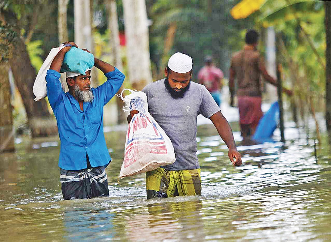 বন্যার পানিতে জনজীবন বিপর্যস্ত। ঢাকার আশপাশের এলাকা প্লাবিত হয়ে পানিবন্দী প্রায় ৮০ হাজার মানুষ। ঈদের দিনে কোরবানির মাংস নিয়ে কোমরপানি ভেঙে চলছেন দুজন। বিকেলে নবাবগঞ্জের দোহার উপজেলার মধুরচর ইউনিয়নে।  ছবি: হাসান রাজা
