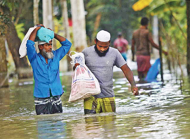 বন্যার পানিতে জনজীবন বিপর্যস্ত। ঢাকার আশপাশের এলাকা প্লাবিত হয়ে পানিবন্দী প্রায় ৮০ হাজার মানুষ। ঈদের দিনে কোরবানির মাংস নিয়ে কোমরপানি ভেঙে চলছেন দুজন। বিকেলে নবাবগঞ্জের দোহার উপজেলার মধুরচর ইউনিয়নে।  ছবি: হাসান রাজা