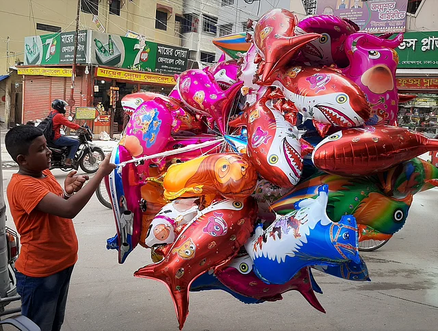 চতুর্থ শ্রেণিতে পড়ুয়া মারুফের বাবা রিকশা চালান। মারুফ এক সপ্তাহ ধরে বেলুন বিক্রি শুরু করছে। বাতাসের দাপটে গ্যাস বেলুনগুলোকে হাতের মুঠোয় ধরে রাখতেই হিমশিম খেতে হয় ছোট মারুফকে। প্রতিটি বেলুনের দাম ৫০ টাকা। মারুফ দিনে ১০ থেকে ১৫টি বেলুন বিক্রি করতে পারে। মোহাম্মদপুর, ঢাকা, ৯ আগস্ট। ছবি: মানসুরা হোসাইন