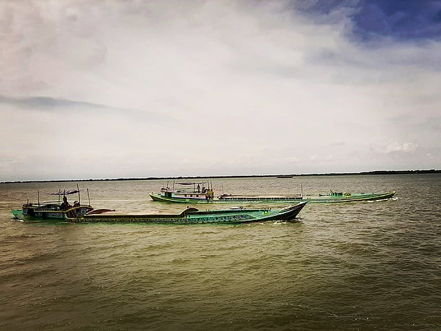 বালুবাহী এই ট্রলারগুলো দেখতে খুবই অদ্ভুত। এক পাশে পানি উঠে ঢেউ হয়ে অন্য পাশে নেমে যায়। দেখে মনে হবে এই যেন ডুবে গেল। মেঘনা নদী। ছবি: আফজাল তাহফি রোহান।