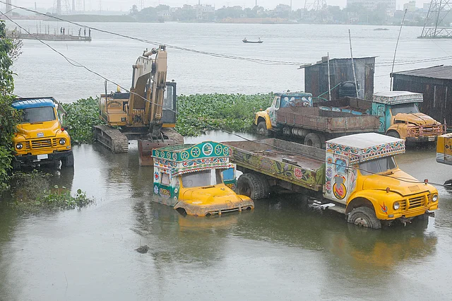 বন্যার পানিতে নদীর তীরে রাখা ট্রাক ও বুলডোজারগুলোর কিছু অংশ তলিয়ে গেছে। গাবতলী, আমিন বাজার, ১০ আগস্ট। ছবি: আশরাফুল আলম