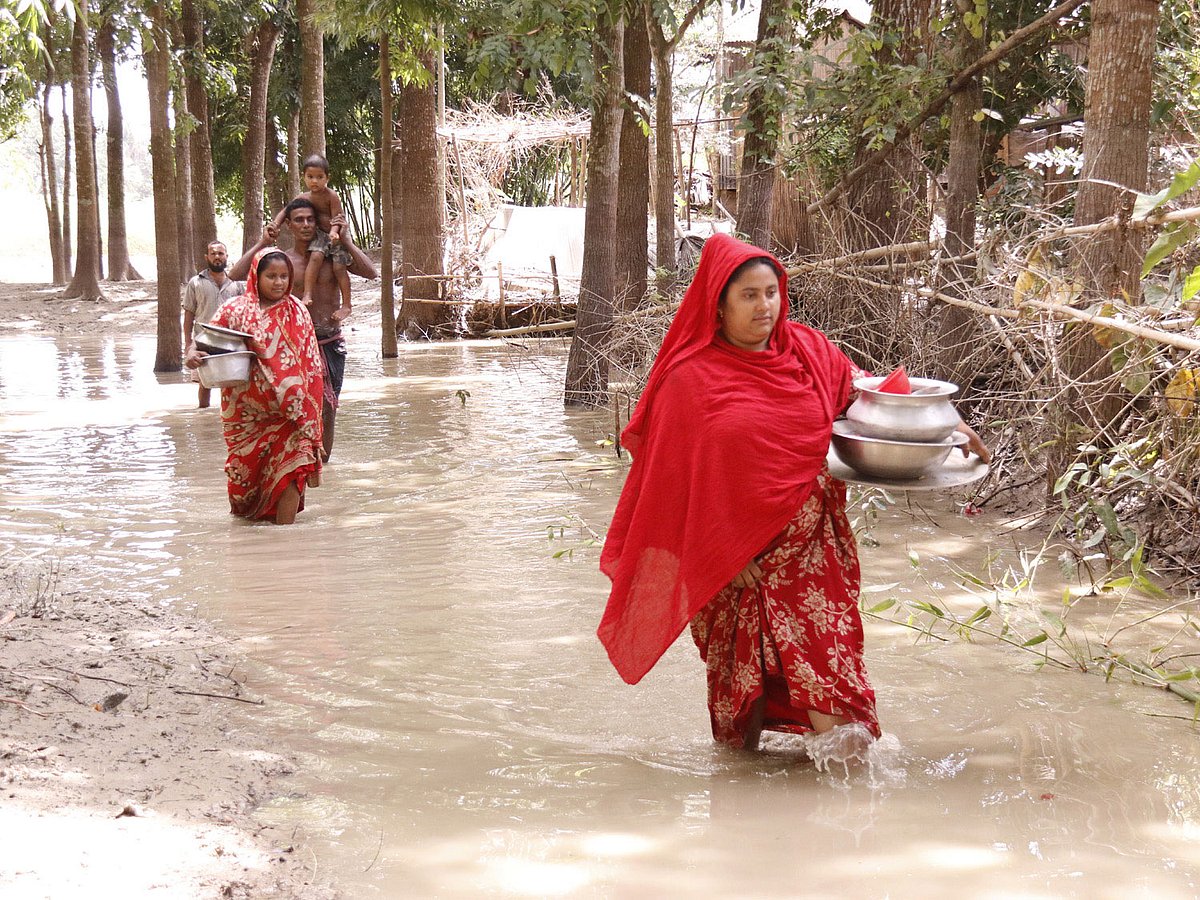 ঘরবাড়ি থেকে বন্যার পানি নেমে গেছে। তবে রাস্তায় পানি রয়ে গেছে। তাই মানুষজনকে পানি মাড়িয়ে চলাচল করতে হচ্ছে। ছবিটি ফরিদপুর সদরের গদাধরডাঙ্গী এলাকা থেকে তোলা। ছবি: প্রথম আলো