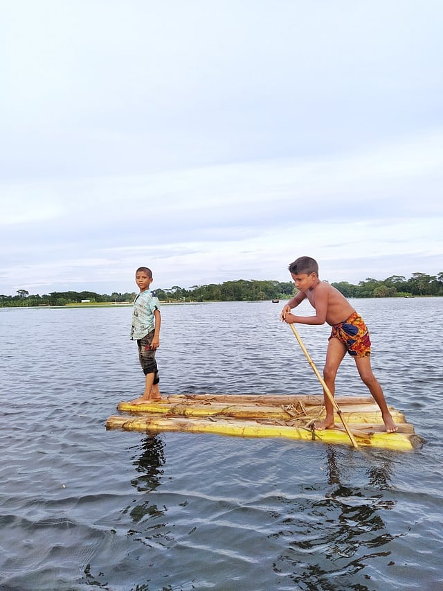 বন্যার পানিতে ভেলায় ঘুরছে দুরন্ত দুই কিশোর। শিবচর, মাদারীপুর, ১১ আগস্ট। ছবি: রাফিন হোসেন অনিক
