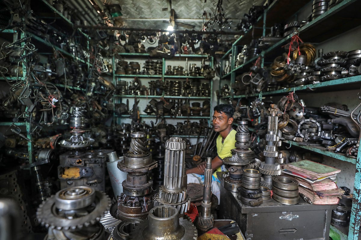 গাড়ির ইঞ্জিনের যন্ত্রাংশ সাজিয়ে দোকানে বসে আছেন এক বিক্রেতা