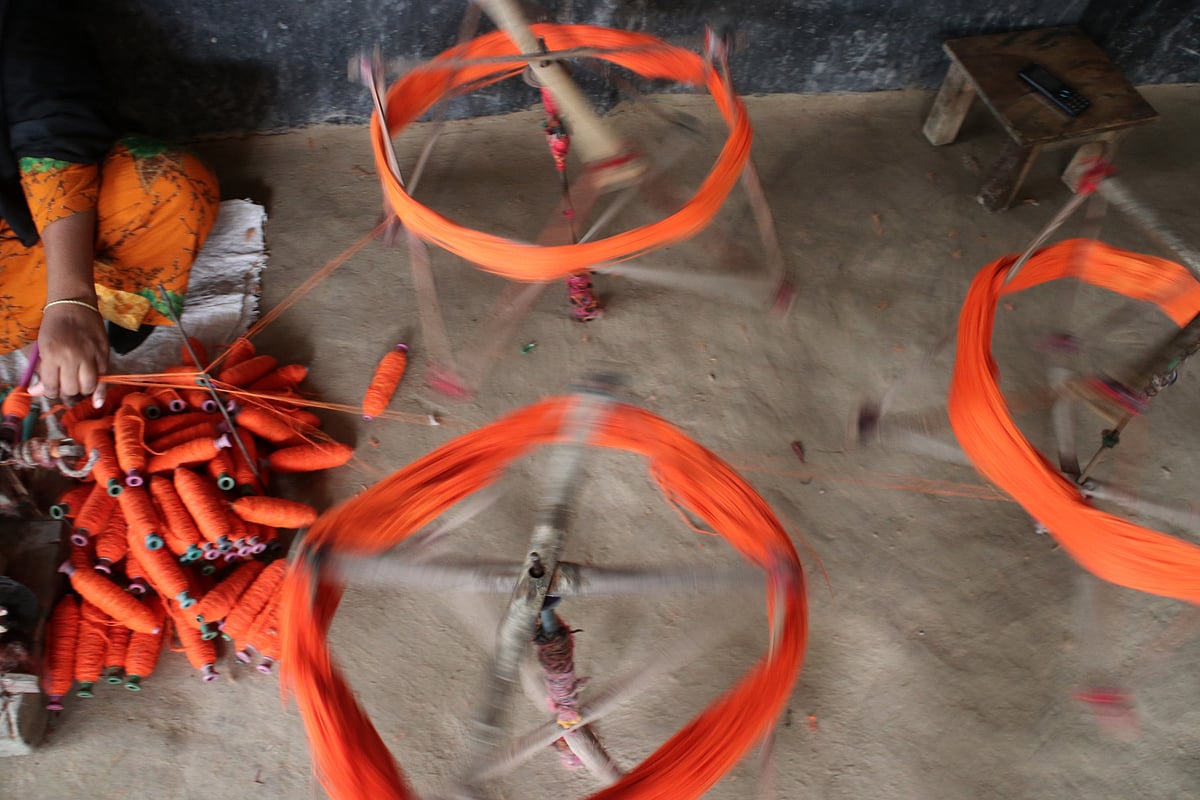 গার্মেন্টস থেকে আনা ফেলনা সুতা বের করে কোণে ভরছেন একজন নারী।