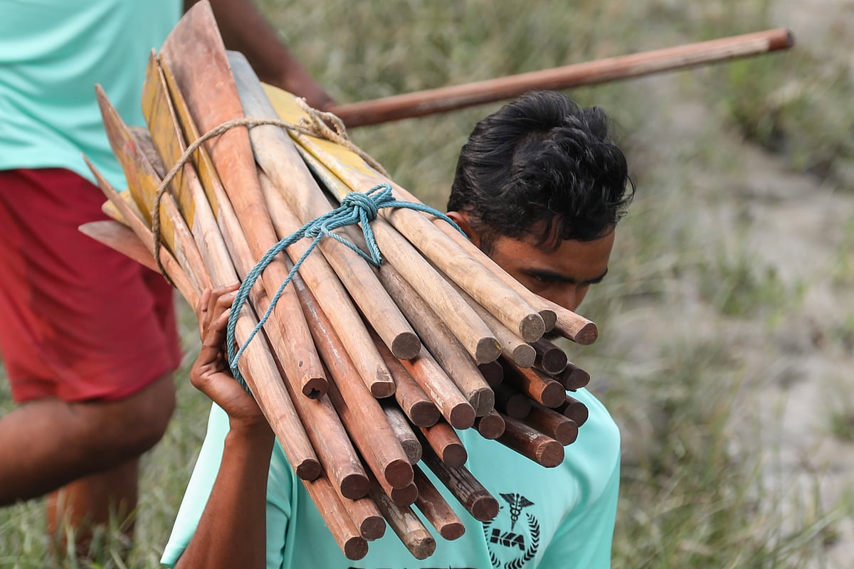 এক প্রতিযোগী বাইচে অংশ নিতে বইঠা নিয়ে নিজের নৌকার দিকে যাচ্ছেন