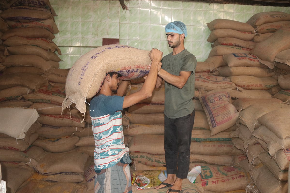 মুড়ির চাল প্রক্রিয়াজাত করার জন্য গোডাউন থেকে চালের বস্তা নিয়ে যাচ্ছেন কারিগরেরা।