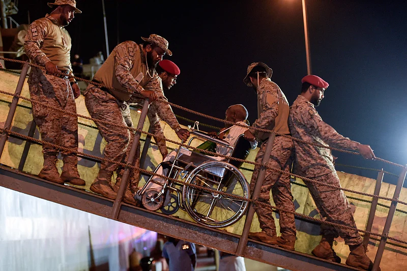 সৌদি আরবের জেদ্দার কিং ফয়সাল নৌঘাঁটিতে পৌঁছানোর পর সুদান থেকে সরিয়ে নেওয়া একজন প্রতিবন্ধী ব্যক্তিকে সহায়তা করছেন সেনারা