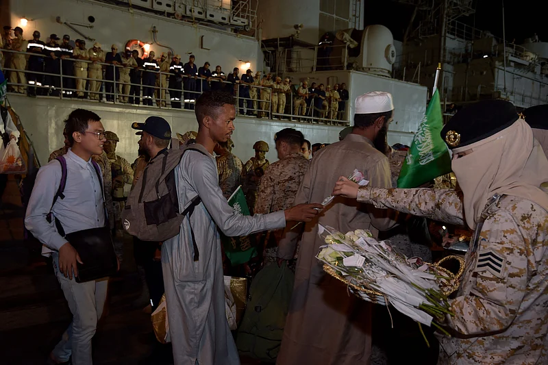 সৌদি আরবের জেদ্দায় কিং ফয়সাল নৌঘাঁটিতে সুদান থেকে সরিয়ে নেওয়া মানুষের মধ্যে গোলাপ ফুল দিয়ে স্বাগত জানানো হচ্ছে