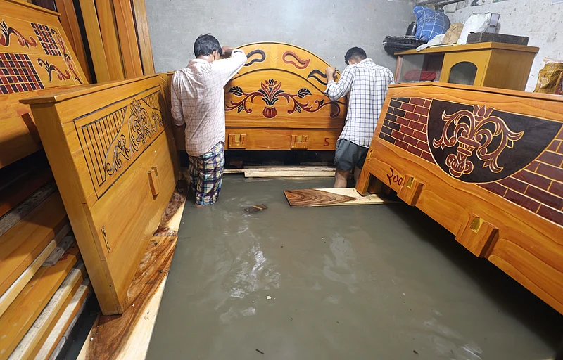 হাঁটুসমান পানি জমে আছে দোকানে। পানি থেকে আসবাব রক্ষার চেষ্টায় ব্যবসায়ীরা।