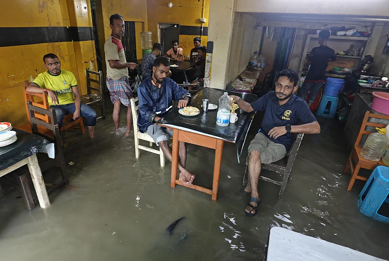 চায়ের দোকানে ঢুকেছে বৃষ্টির পানি। এর মধ্যেই চলছে রান্না ও খাওয়া