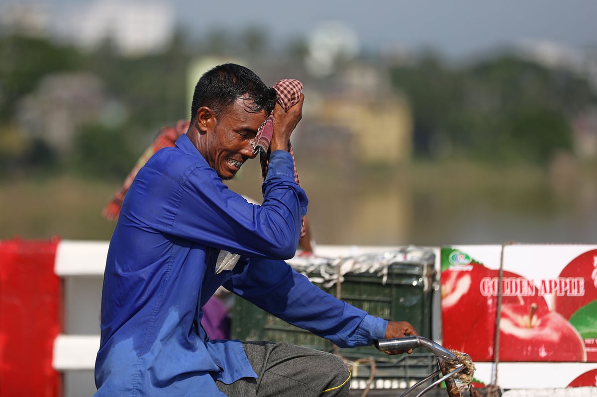 গরমে ঘেমে একাকার এই ভ্যানচালক গামছা দিয়ে ঘাম মুছে নিচ্ছেন। শাহজালাল সেতু, সিলেট। 