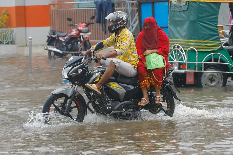 জলমগ্ন সড়কে পা ওপরে তুলে মোটরসাইকেল চালাচ্ছেন তিনি। 