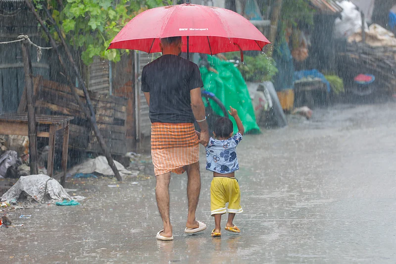 বৃষ্টির মধ্যে বাবার সঙ্গে বাইরে বের হয়েছে এক শিশু।