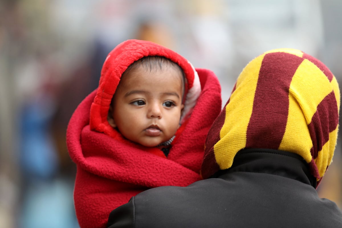 শিশুকে কম্বলে জড়িয়ে বাইরে বের হয়েছেন এক অভিভাবক।