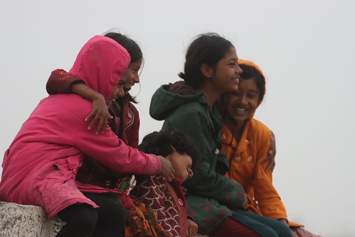 শীতের সকালে সেতুতে বসে দুষ্টুমিতে মেতেছে কয়েকটি শিশু।