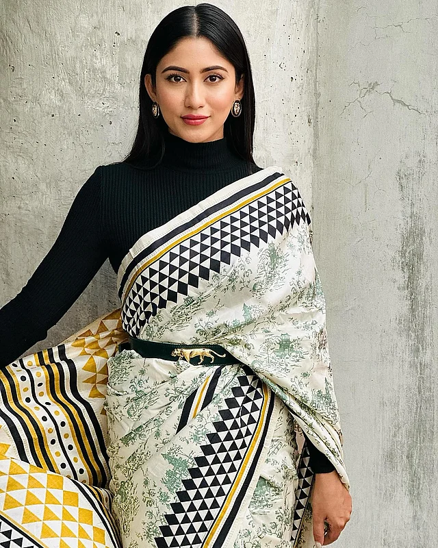 সাফা কবিরের চেকারবোর্ড প্যাটার্নের সাদাকালো পাড়ের প্রিন্টের শাড়িতে শর্ষে হলুদের পরিমিত ছোঁয়া। সঙ্গে টারটলনেক কালো ফুলস্লিভ ব্লাউজ। বাঘের প্রতিকৃতি দেওয়া কালো বেল্ট নজর কাড়ছে। 