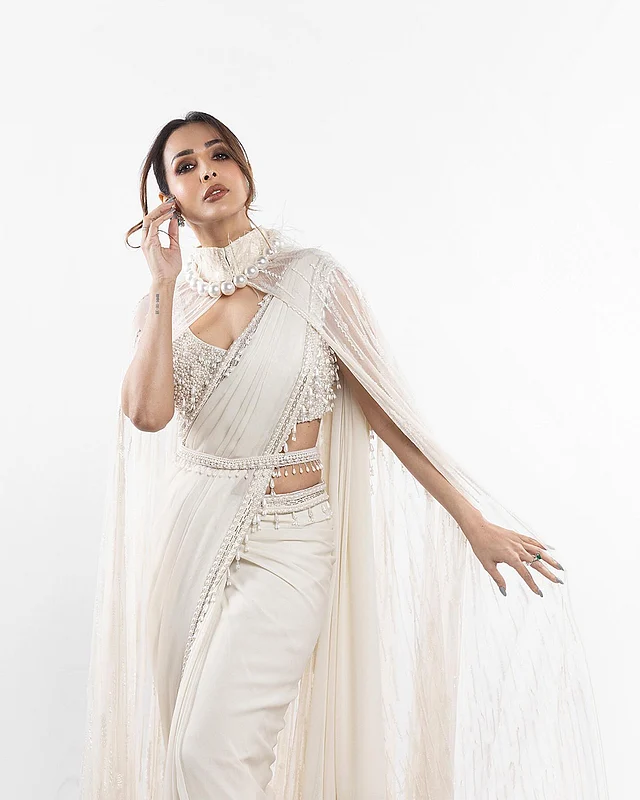 পার্ল এমবেলিশমেন্ট করা স্লিভলেস ব্লাউজের সঙ্গে মালাইকা অরোরা পরেছেন পার্লের পাড়সহ একটি মনোক্রোম শাড়ি। সঙ্গে জুটি বেঁধেছে কোমরে পরা পার্লের বেল্ট। আর তাঁর পোশাকের আকর্ষণ বাড়িয়েছে মুক্তা বসানো কলারের কেপ।
