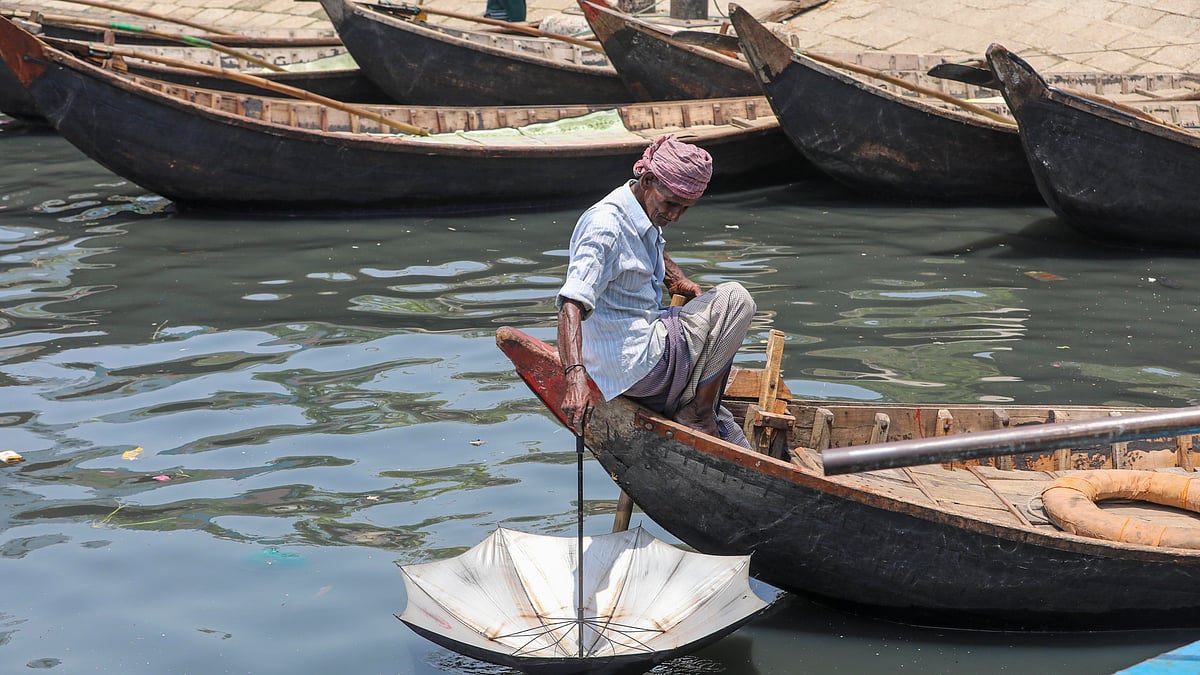 প্রচণ্ড রোদে তপ্ত হয়ে উঠেছে ছাতা, তাই ছাতাকে নদীর পানিতে ভিজিয়ে নিচ্ছেন তিনি। শ্যামবাজার ঘাট, ২৯ এপ্রিল